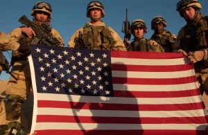 Army 82nd Airborne Division soldiers from Company D, 1st Battalion, 325th Airborne Infantry Regiment, Fort Bragg, N.C., pose behind the American flag after training in urban combat at the Udary range in northern Kuwait. The soldiers are from left to right: Pfc. Robert Crisher, Sgt. Justin Brown, Pfc. Brandan Parra, Sgt. Gregory Rivera and Staff Sgt. Andrew Mangrum.